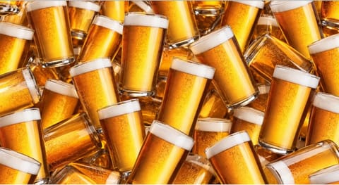 Dozens of full plastic cups of beer piled together.