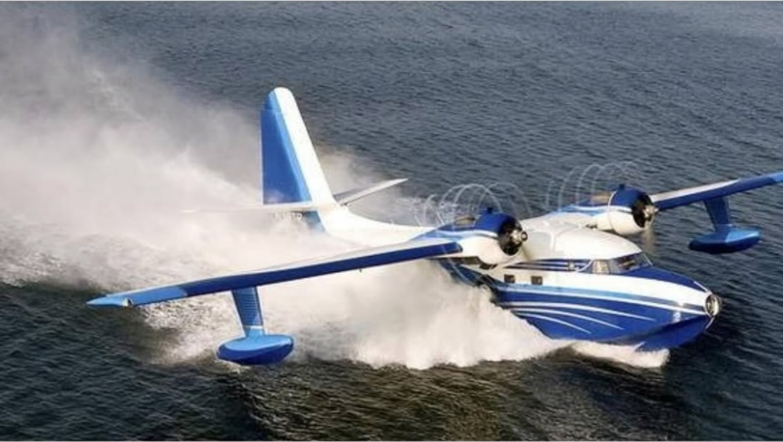 A blue and white seaplane skimming across the water.