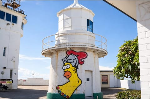 A cartoon chicken in a knight's helmet painted on the base of a white lighthouse.