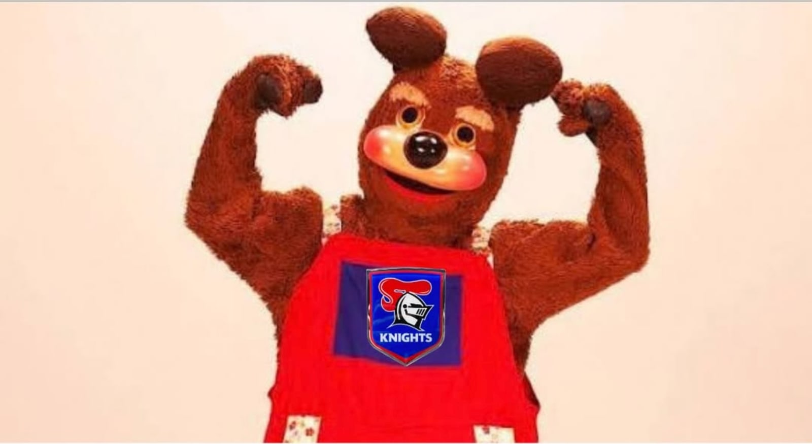 A bear mascot in red overalls flexing both arms.