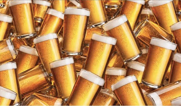 Dozens of full plastic cups of beer piled together.